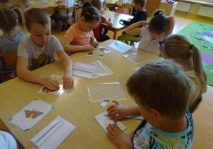 Dzieci układają obrazki z części przedstawiające zwierzęta zamieszkujące łąkę.